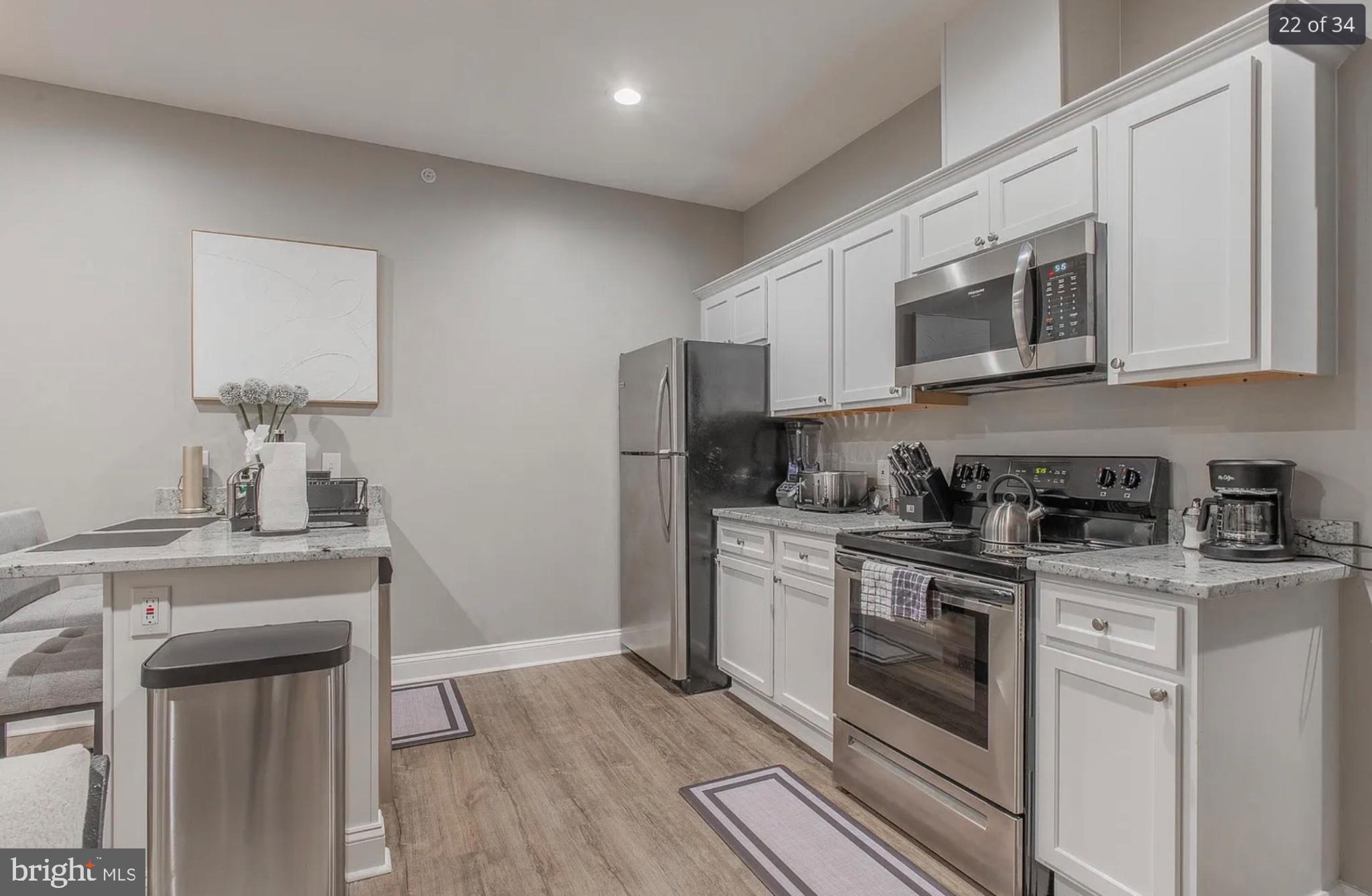 3221 Noble Street, Unit 3 Baltimore, MD 21224 - Photo 3 of 20 a kitchen with stainless steel appliances granite countertop a stove a sink and a refrigerator