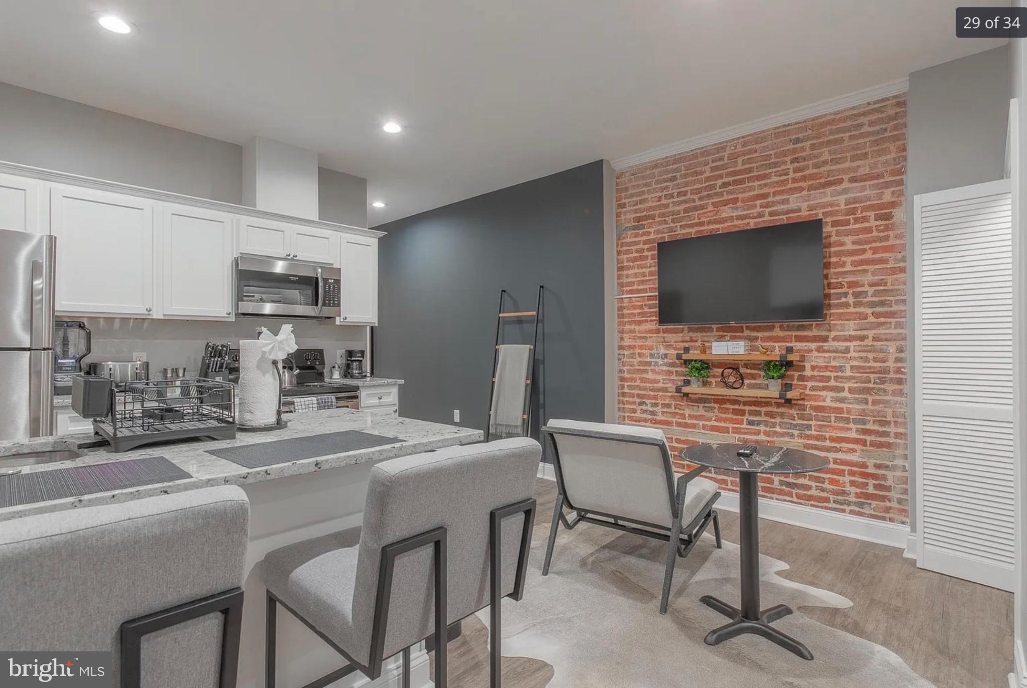3221 Noble Street, Unit 3 Baltimore, MD 21224 - Photo 7 of 20 a kitchen with kitchen island a dining table chairs cabinets and stainless steel appliances
