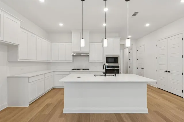 a kitchen with kitchen island a sink stainless steel appliances and cabinets