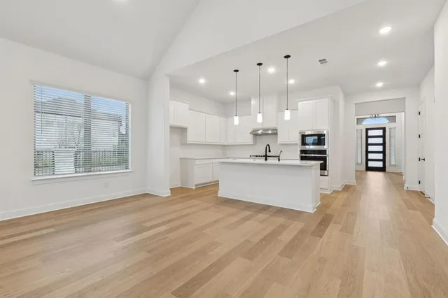 a view of a livingroom with wooden floor a ceiling fan and windows