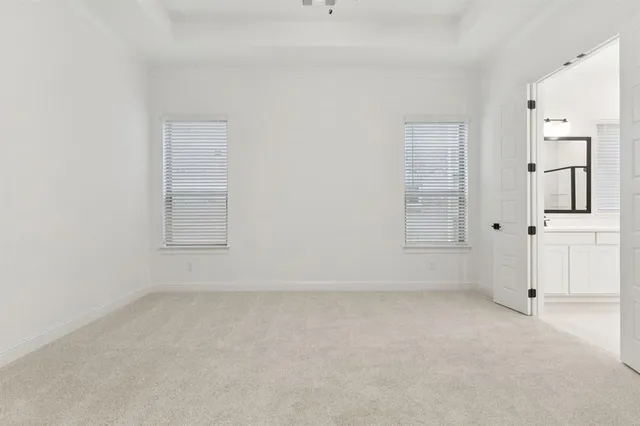 an empty room with a chandelier fan and windows