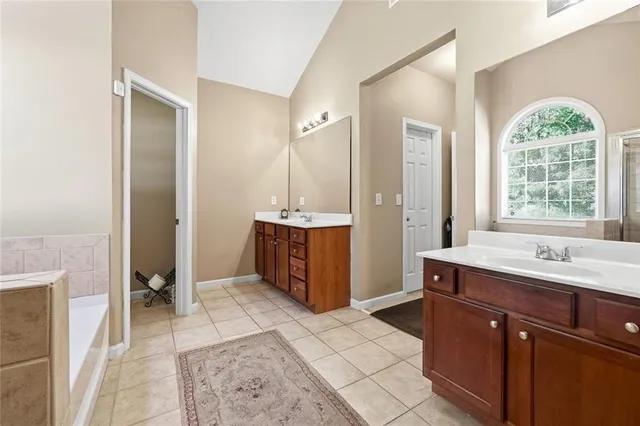 a spacious bathroom with a tub sink and mirror