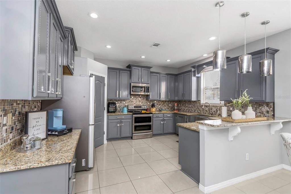 14818 Edgemere Drive Spring Hill, FL 34609 - Photo 11 of 72 a kitchen with stainless steel appliances granite countertop a sink stove and refrigerator