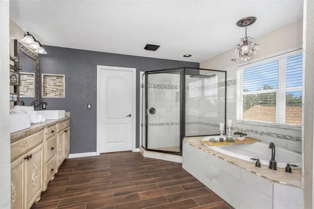 a spacious bedroom with a bed a mirror on dresser and a flat screen tv