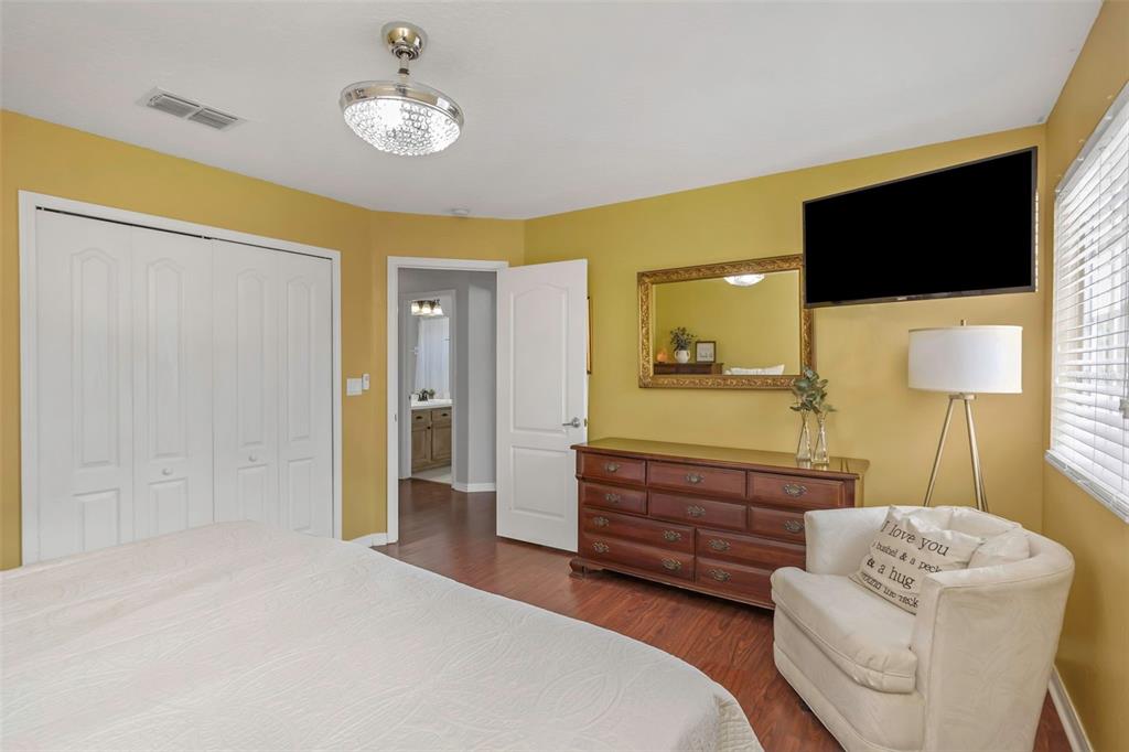 14818 Edgemere Drive Spring Hill, FL 34609 - Photo 29 of 72 a spacious bedroom with a bed a mirror on dresser and a flat screen tv