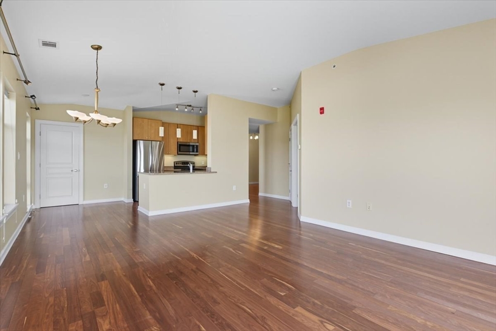 4 Repton Place, Unit 4410 Watertown, MA 02472 - Photo 6 of 41 a view of an empty room with wooden floor and a window