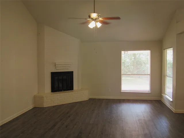 an empty room with wooden floor ceiling fan and windows