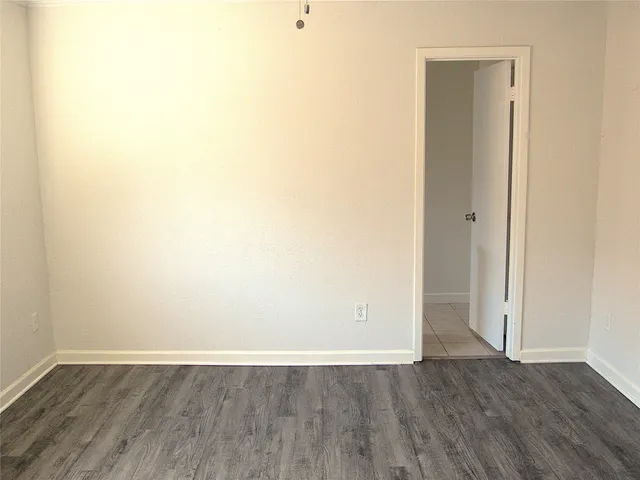 a view of an empty room with wooden floor and closet