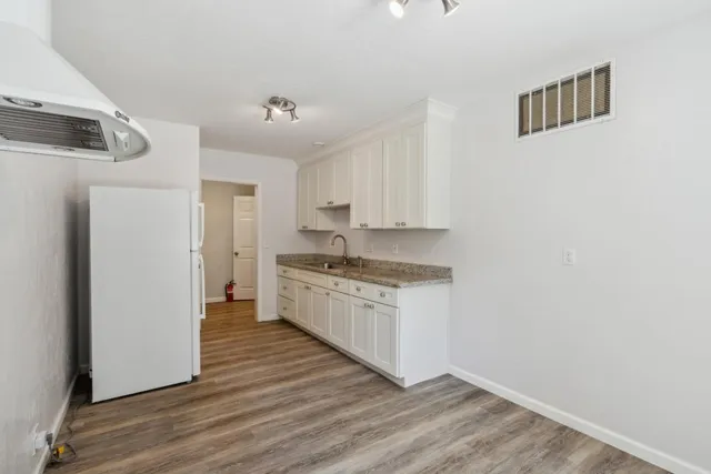 a backyard of a house with plants and trees with wooden fence