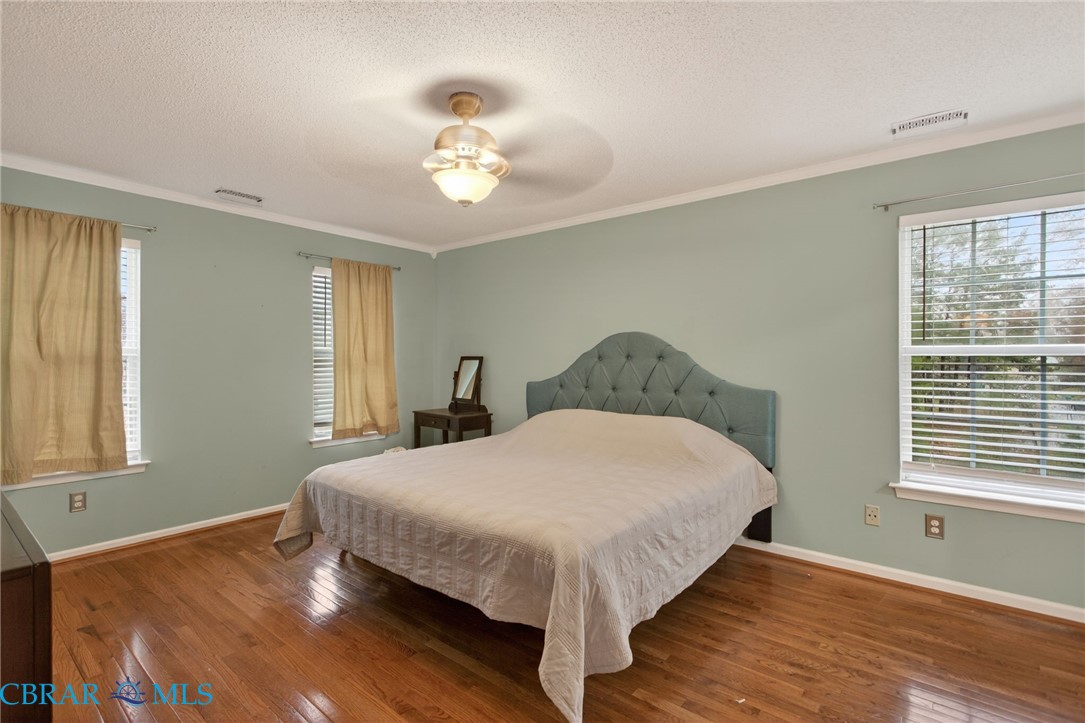 116 Old Field Road Williamsburg, VA 23188 - Photo 18 of 27 Bedroom featuring hardwood / wood-style floors, a textured ceiling, multiple windows, a ceiling fan, and crown molding