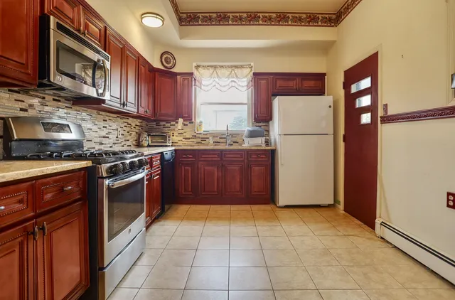 a kitchen with stainless steel appliances granite countertop a stove top oven a refrigerator and a cabinets with wooden floor