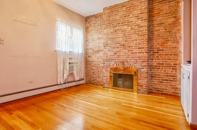 a view of empty room with a fireplace and wooden floor