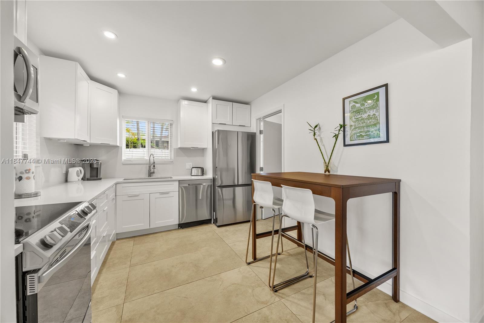 3246 Pierce Street Hollywood, FL 33021 - Photo 10 of 41 a kitchen with a table chairs refrigerator and cabinets