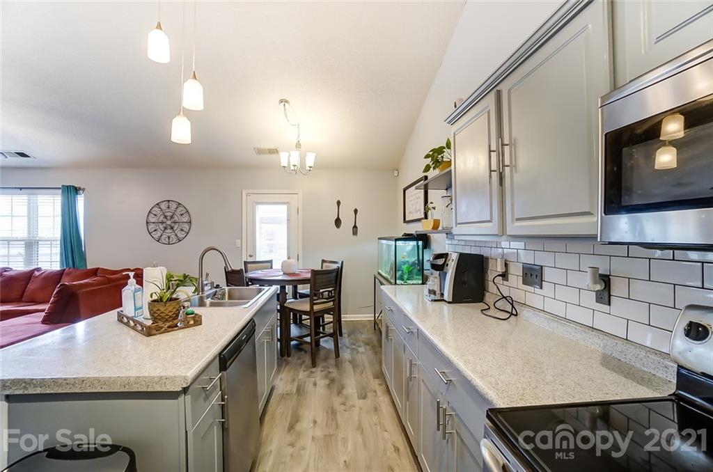7034 Blithe Low Place Charlotte, NC 28273 - Photo 12 of 31 a kitchen with a sink a stove and chairs