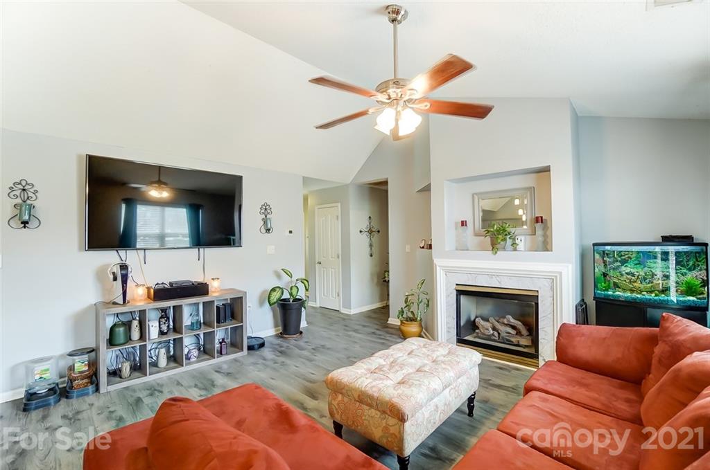 7034 Blithe Low Place Charlotte, NC 28273 - Photo 8 of 31 a living room with furniture a flat screen tv and a fireplace