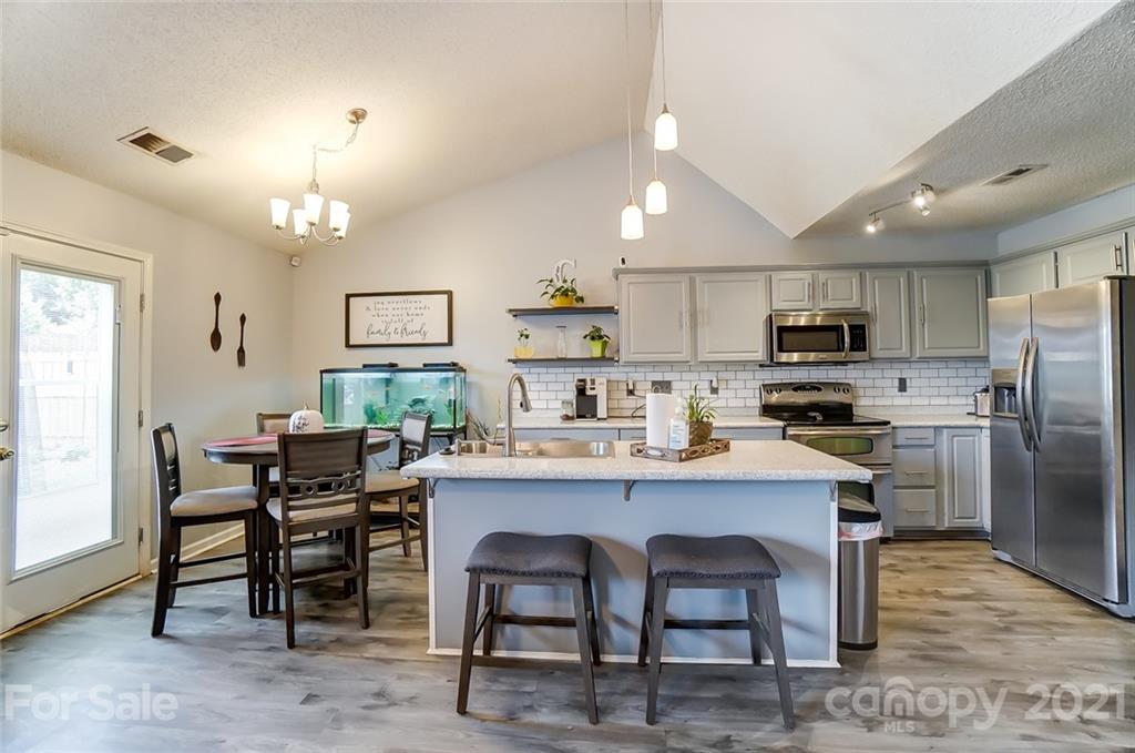 7034 Blithe Low Place Charlotte, NC 28273 - Photo 10 of 31 a kitchen with cabinets a sink stainless steel appliances and dining table