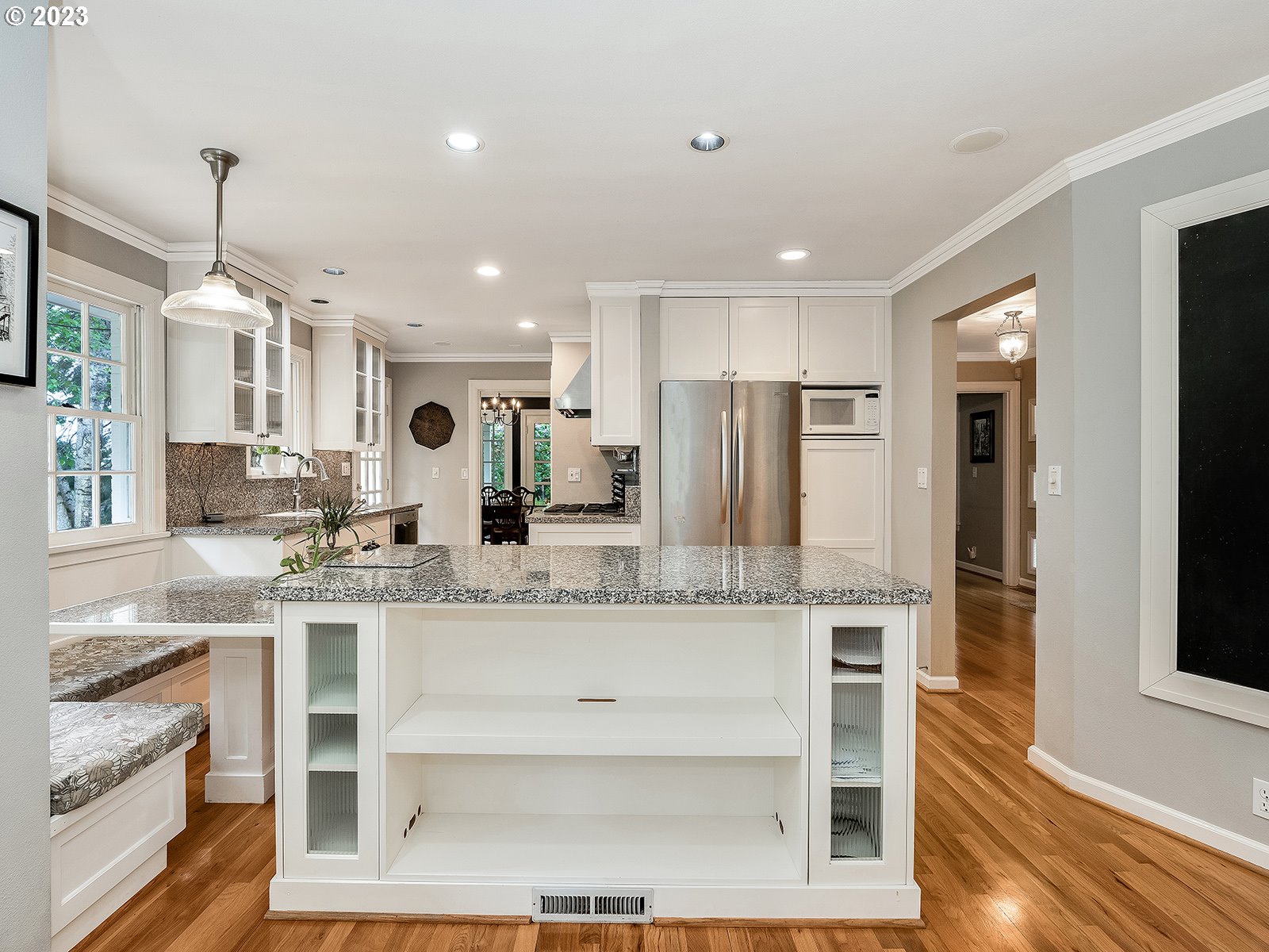 2828 Southwest Sunset Boulevard Portland, OR 97239 - Photo 13 of 32 a large white kitchen with a center island wooden floor and stainless steel appliances