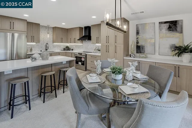 a kitchen with stainless steel appliances kitchen island granite countertop a table chairs refrigerator and microwave