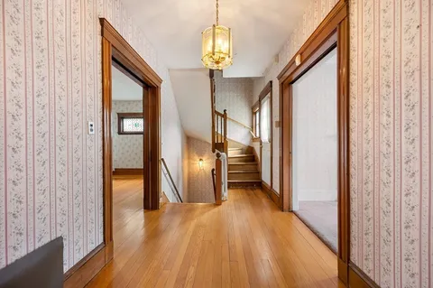 a view of a hallway with wooden floor and chandelier