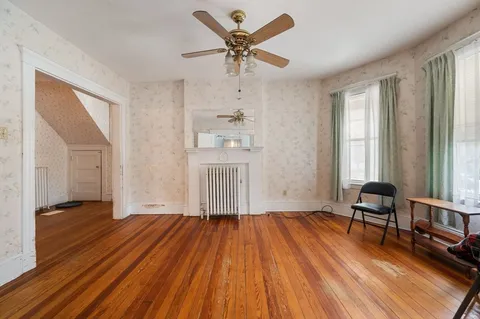 a view of empty room with wooden floor and fan