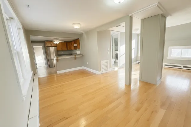 a view of a big room with wooden floor and windows