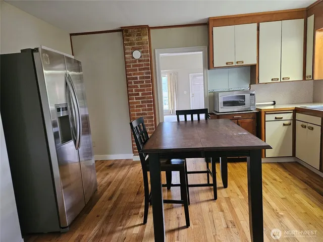a kitchen with stainless steel appliances a dining table chairs and refrigerator