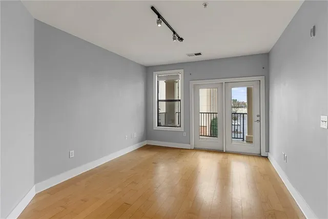 a view of an empty room with window and wooden floor
