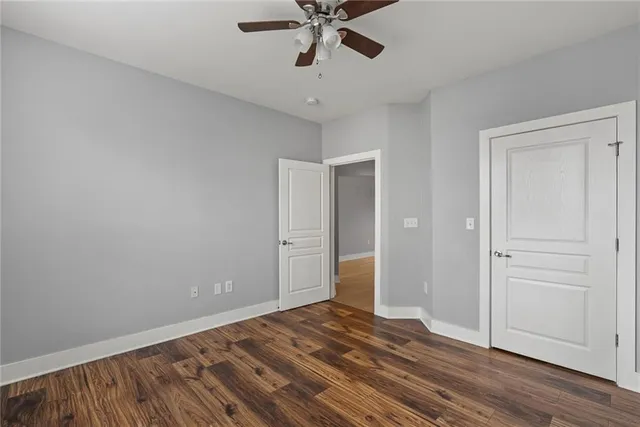 a view of empty room with wooden floor and ceiling fan