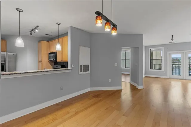 a view of an empty room with wooden floor and a window
