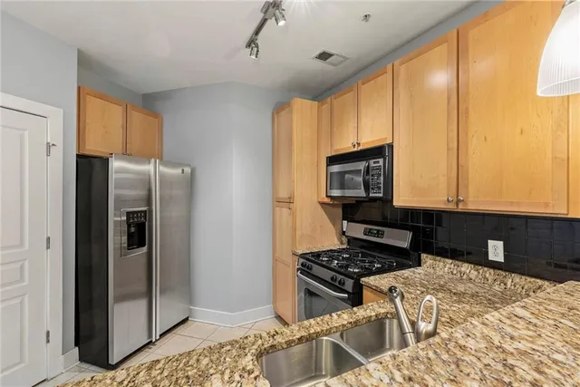 a kitchen with stainless steel appliances granite countertop a refrigerator and a stove top oven