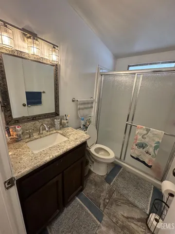 a bathroom with a granite countertop sink toilet and shower