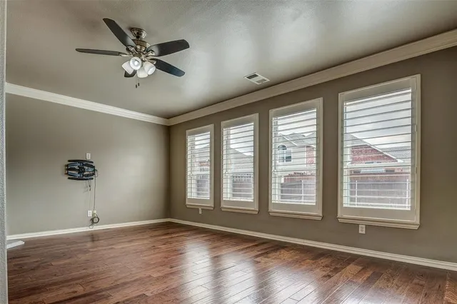 a view of an empty room with a window and wooden floor
