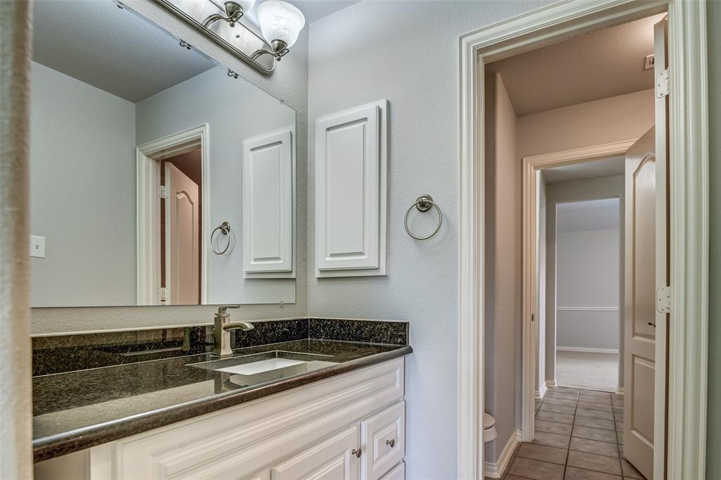 916 Carlsbad Drive Allen, TX 75002 - Photo 27 of 34 a bathroom with a granite countertop sink a mirror and a vanity
