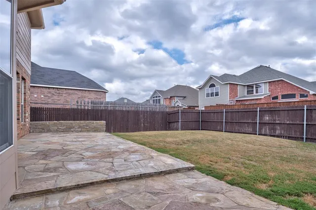 a view of a brick house with a yard and wooden fence