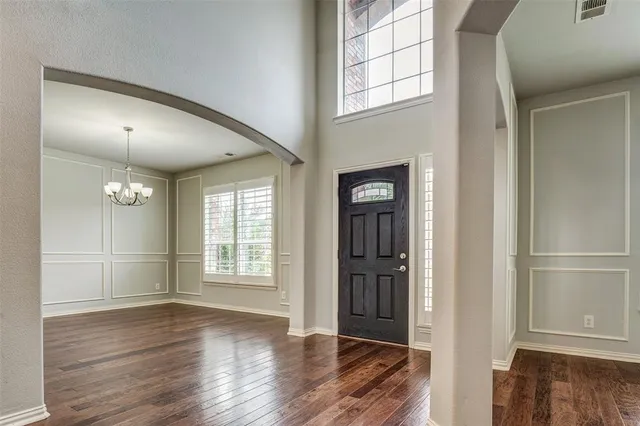 an empty room with wooden floor cabinet and windows