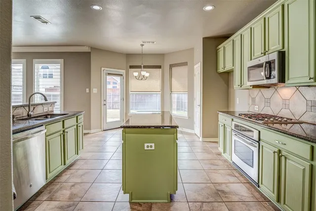 a kitchen with stainless steel appliances granite countertop a stove a sink and a microwave