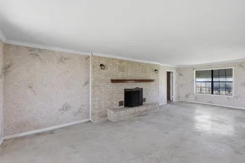 an empty room with windows and fireplace