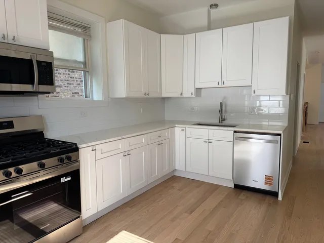 a kitchen with granite countertop white cabinets and stainless steel appliances