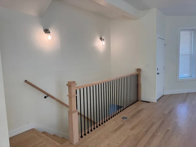 a view of a hallway with wooden floor and stairs