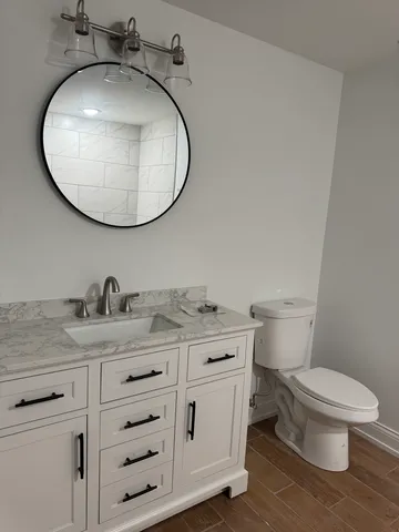 a bathroom with a granite countertop toilet sink and mirror