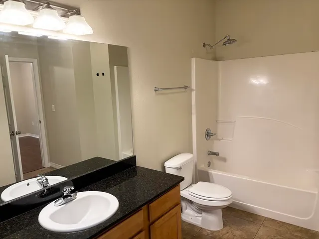 a bathroom with a granite countertop sink toilet a mirror and shower