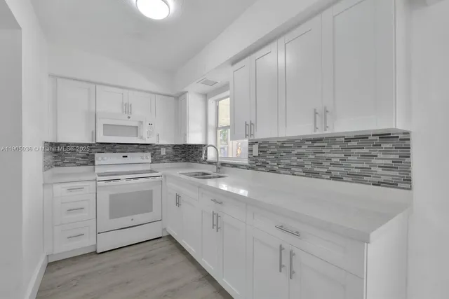 a kitchen with granite countertop white cabinets and white stainless steel appliances