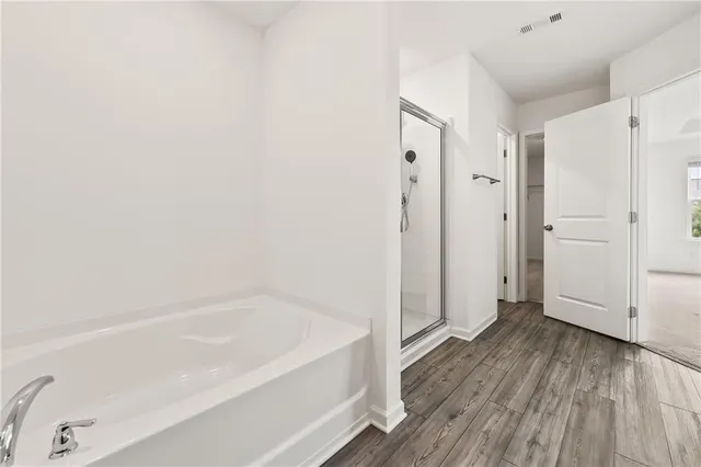 a spacious bathroom with a bathtub and a wooden floor