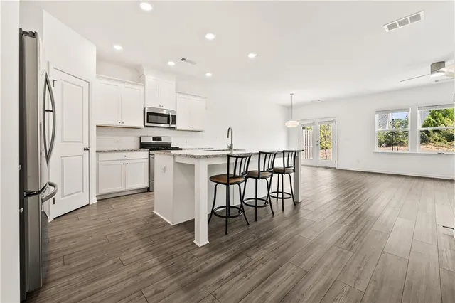 a kitchen with stainless steel appliances a dining table chairs microwave and cabinets