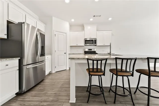a kitchen with kitchen island white cabinets and stainless steel appliances
