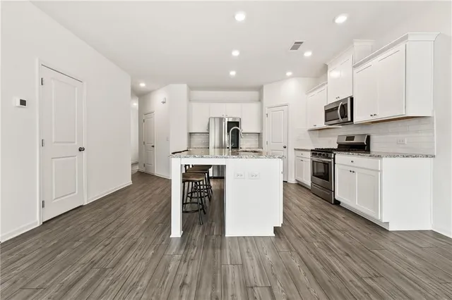 a kitchen with stainless steel appliances kitchen island wooden floors and white cabinets