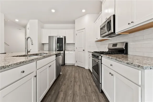 a large kitchen with stainless steel appliances granite countertop a stove top oven a sink and dishwasher