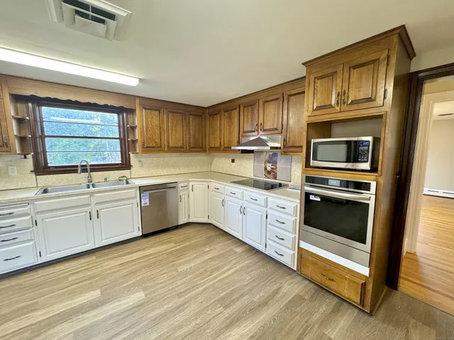 a kitchen with stainless steel appliances granite countertop a stove a sink and a microwave
