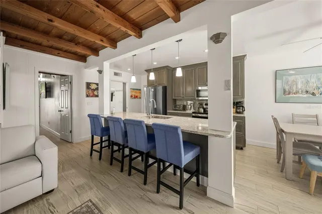 a kitchen with stainless steel appliances granite countertop a stove top oven a sink a refrigerator white cabinets and wooden floor