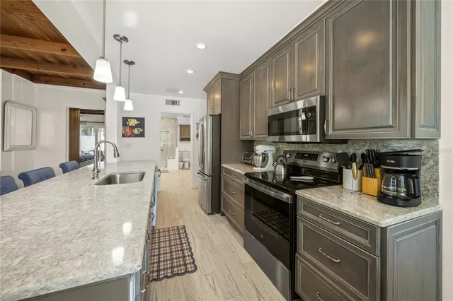 a kitchen with stainless steel appliances granite countertop a refrigerator a oven and a sink with couches